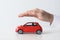 Male insurance agent covering toy car on white background