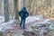 Male in a jacket stands on a forest path and looks at the trees in front of him