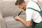 Male janitor removing dirt from sofa