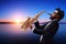 Male jazz musician playing a saxophone with a sunset and water