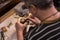 A male jeweler fixes precious stones on a silver pendant.