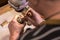 A male jeweler fixes precious stones on a silver pendant.