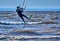 A male kiteboarder jumps above the surface of the water of a large river.