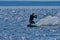 A male kiteboarder rides on a board on a large river.