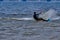 A male kiteboarder rides on a board on a large river.