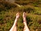 Male legs on dry heather bush. Tired legs on rocky peak bove landscape. Pure pink skin, clear nails.