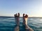 Male legs, feet with fingers spread out in a beautiful blue wet azure natural clear water against a blue sky and horizon line in a