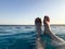 Male legs, feet with fingers spread out in a beautiful blue wet azure natural clear water against a blue sky and horizon line in a