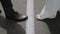 Male legs in shoes, female legs in sandals make a step white line on road