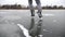 Male legs of skater shod in figure skates sliding on ice rink at nature. Feet of sportsman training on frozen river