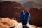 Male legs in sneakers over cliff against backdrop of mountain.