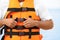 Male lifeguard putting on life vest near sea, closeup