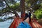 A male man guy laying on the hammock swing on the beach during summertime with a view of pines and blue sea with healthy fresh air