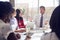 Male manager sits talking to colleagues in a meeting room