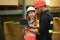 Male manager and warehouse worker inspecting stock tick and cardboard stock product on digital tablet in a large