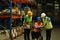 Male manager in wheelchair and young workers inspecting stock tick and cardboard stock product in a large warehouse