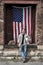 Male manual worker with hard hat, tool belt, American flag at factory loading dock