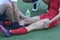 Male massagist hands massaging leg of the woman football player on the soccer field