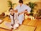 Male masseur doing massage woman in bamboo spa.