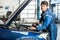 Male Mechanic Filling Oil Into Car\'s Engine At Garage