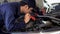 Male mechanic holding and shining flashlight to checking car engine problem