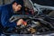 Male mechanic holding and shining flashlight to checking car engine problem