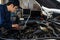 Male mechanic using laptop while repairing car in auto service