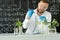 Male microbiologist adding biological nutritional supplement, vitamins and minerals from a syringe to growing green