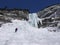 Male mountain climber rapelling off a steep and long frozen waterfall in the Swiss Alps in deep winter