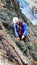 Male mountain guide building a traditional belay stance with pitons to rappel from a high alpine peak