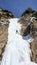 Male mountain guide rappelling off a steep frozen waterfall after an ice climbing excursion