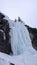 Male mountain guide rappelling off a steep frozen waterfall after an ice climbing excursion