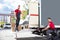 Male Movers Loading Cardboard Boxes In Truck On Street