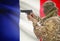 Male in muslim keffiyeh with gun in hand and national flag on background - France
