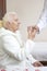 Male nurse gives a glass of water to the old woman during medication.