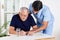 Male Nurse Helping Senior Man In Solving Puzzle
