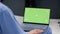 Male nurse holding laptop with greenscreen template in waiting room