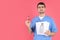 Male nurse holds magnifier and vision test on pink background