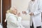 Male nurse supervises taking medicine by an old woman.