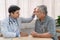 Male ophthalmologist doctor examining elderly patient eye at home