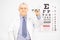 Male optician holding glasses in front of an eye chart