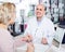 Male optician offering glasses frames to elderly woman