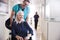 Male Orderly Pushing Senior Female Patient Being Discharged From Hospital In Wheelchair