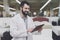 A male orthopedic pose against the background of a large store of beds. He holds tablet in his hands and looks at him.