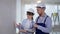 male painter and female designer in hard hats discuss wall paint from a color palette during interior finishing work