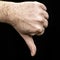 Male palm clenched into a fist thumb pointing down on the black background gesture dislike