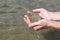 Male palms with damp river sand against of the water