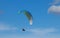 Male paragliding against a cloudy blue sky