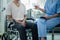 Male patient sitting in wheelchair undergoing a medical examination with specialist physician, treating injuries Getting medical