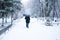 A male pedestrian is hiding from the snow under an umbrella in the park